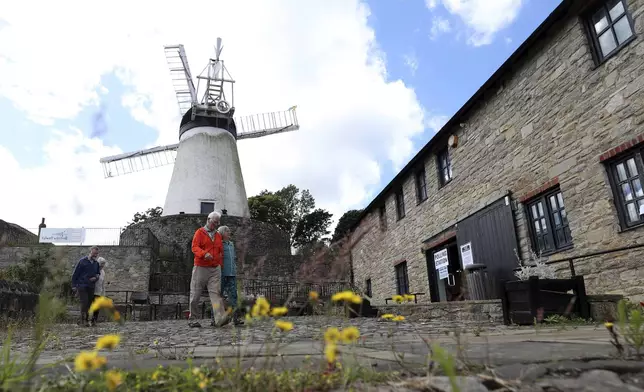 People walk from Falwell windmill and mill which is a temporary polling station, after casting their vote in Sunderland, England, Thursday, July 4, 2024.Britain goes to the polls Thursday after Prime Minister Rishi Sunak called a general election. (AP Photo/Scott Heppell)