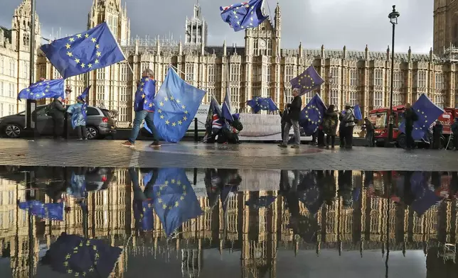 FILE - Protestors are reflected in a large puddle as they wave European flags to demonstrate against Brexit in front of the Parliament in London, Dec. 3, 2018. The U.K. election in December 2019 was basically about one issue: Brexit. General elections in the U.K. are typically held in the spring or early summer. But in the fall of 2019, the recently-appointed Prime Minister Boris Johnson gambled on holding one on December 12, when most people just want to get ready for Christmas and would rather think of anything but politics. (AP Photo/Frank Augstein, File)
