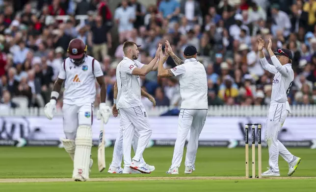England's Gus Atkinson and Zak Crawley celebrate with team mates following the wicket of West Indies' Kirk Mckenzie, not in picture, on day one of the first Rothesay Men's Test match at Lord's Cricket Ground, London, Wednesday, July 10, 2024. (Steven Paston/PA via AP)