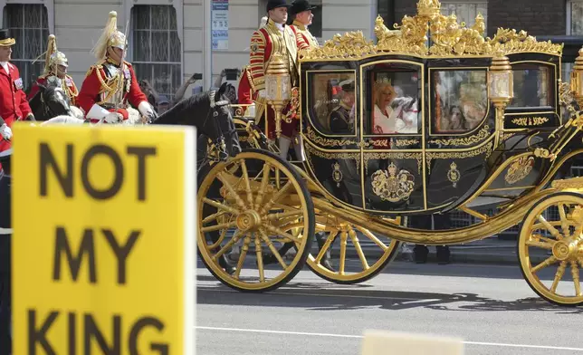 Anti-monarchy Not My King protesters demonstrate as King Charles III and Queen Camilla ride past in their carriage to the Houses of Parliament ahead of the State Opening of Parliament in the House of Lords, London, Wednesday, July 17, 2024. King Charles III's speech will set out the agenda of the UK's first Labour government for 14 years. (AP Photo/Kin Cheung)