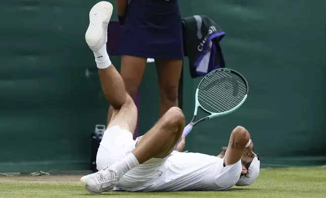 Lorenzo Musetti of Italy falls to the ground as he celebrates after defeating Giovanni Mpetshi Perricard of France in their fourth round match at the Wimbledon tennis championships in London, Monday, July 8, 2024. (AP Photo/Mosa'ab Elshamy)