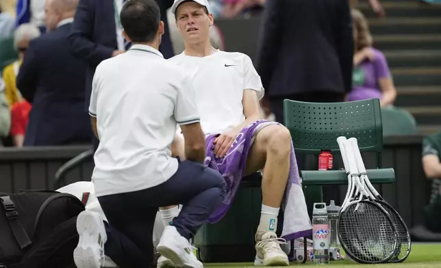 Jannik Sinner of Italy reacts as he receives treatment from a trainer during his quarterfinal match against Daniil Medvedev of Russia at the Wimbledon tennis championships in London, Tuesday, July 9, 2024. (AP Photo/Alberto Pezzali)