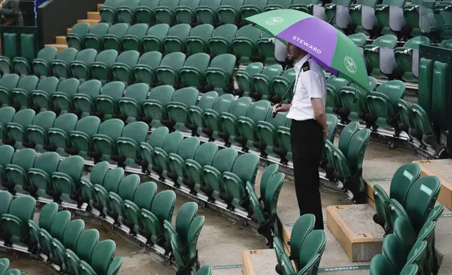 A court steward stands under an umbrella on an outside court as rain delays the start of play at the Wimbledon tennis championships in London, Saturday, July 6, 2024. (AP Photo/Alberto Pezzali)