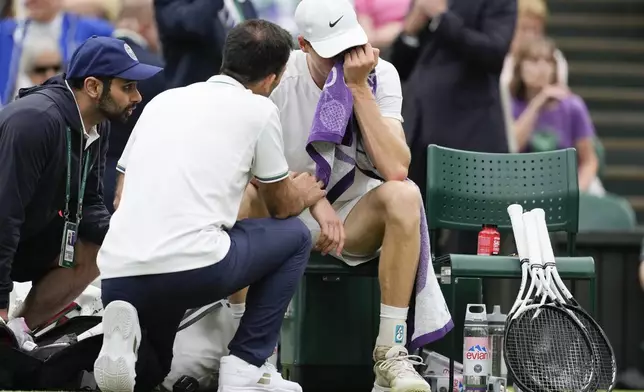 Jannik Sinner of Italy reacts as he receives treatment from a trainer during his quarterfinal match against Daniil Medvedev of Russia at the Wimbledon tennis championships in London, Tuesday, July 9, 2024. (AP Photo/Alberto Pezzali)