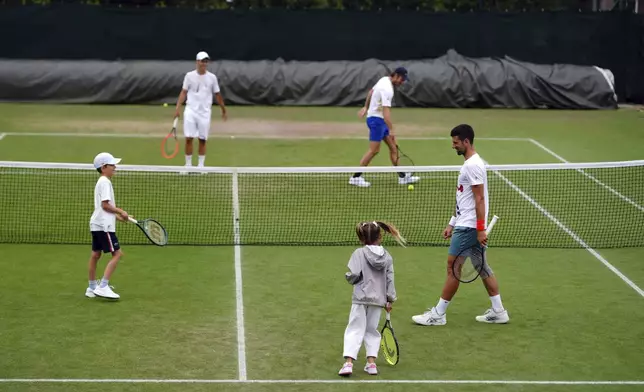 Serbia's Novak Djokovic reacts with with his daughter, Tara, and son, Stefan during a practice session, at the Wimbledon tennis championships in London, Wednesday, July 10, 2024. (John Walton/PA via AP)