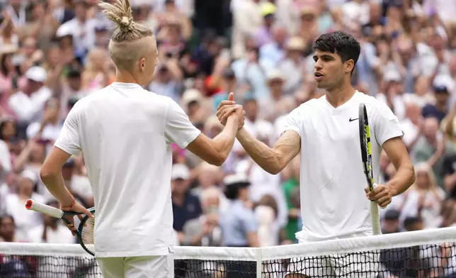 Carlos Alcaraz, right, of Spain is congratulated Mark Lajal of Estonia following their first round match at the Wimbledon tennis championships in London, Monday, July 1, 2024. (AP Photo/Alberto Pezzali)