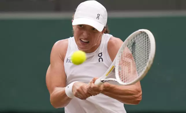 Iga Swiatek of Poland plays a backhand return to Yulia Putintseva of Kazakhstan during their third round match at the Wimbledon tennis championships in London, Saturday, July 6, 2024. (AP Photo/Alberto Pezzali)