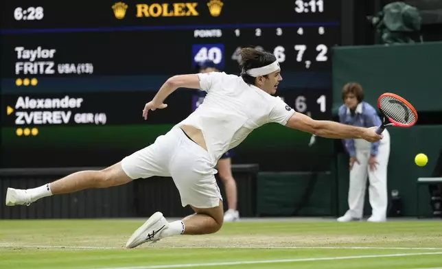 Taylor Fritz of the United States falls as he attempts to make a backhand return to Alexander Zverev of Germany during their fourth round match at the Wimbledon tennis championships in London, Monday, July 8, 2024. (AP Photo/Kirsty Wigglesworth)