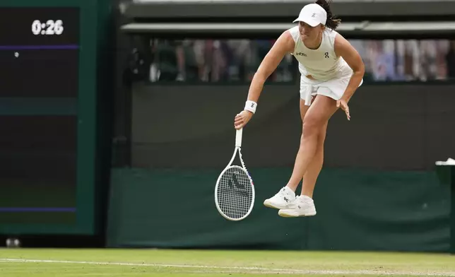 Iga Swiatek of Poland serves to Yulia Putintseva of Kazakhstan during their third round match at the Wimbledon tennis championships in London, Saturday, July 6, 2024. (AP Photo/Alberto Pezzali)