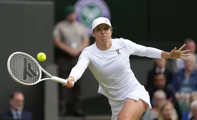 Iga Swiatek of Poland plays a forehand return to Petra Martic of Croatia during their second round match at the Wimbledon tennis championships in London, Thursday, July 4, 2024. (AP Photo/Kirsty Wigglesworth)