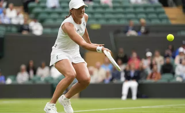 Iga Swiatek of Poland plays a forehand return to Yulia Putintseva of Kazakhstan during their third round match at the Wimbledon tennis championships in London, Saturday, July 6, 2024. (AP Photo/Alberto Pezzali)