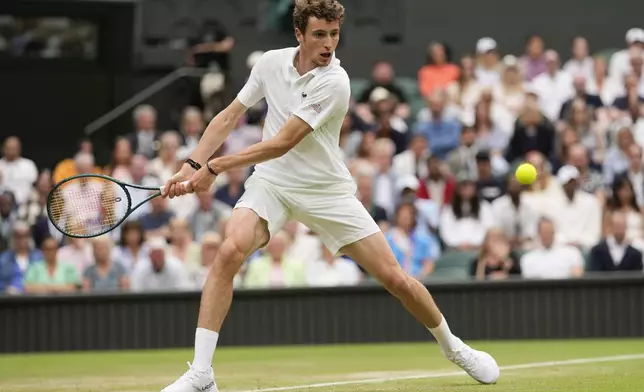 Ugo Humbert of France plays a backhand return to Carlos Alcaraz of Spain during their fourth round match at the Wimbledon tennis championships in London, Sunday, July 7, 2024. (AP Photo/Alberto Pezzali)