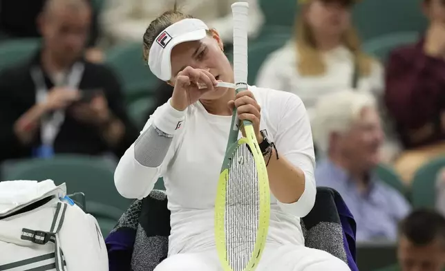 Barbora Krejcikova of the Czech Republic puts tape around her racket handle during her fourth round match against Danielle Collins of the United States at the Wimbledon tennis championships in London, Monday, July 8, 2024. (AP Photo/Alberto Pezzali)