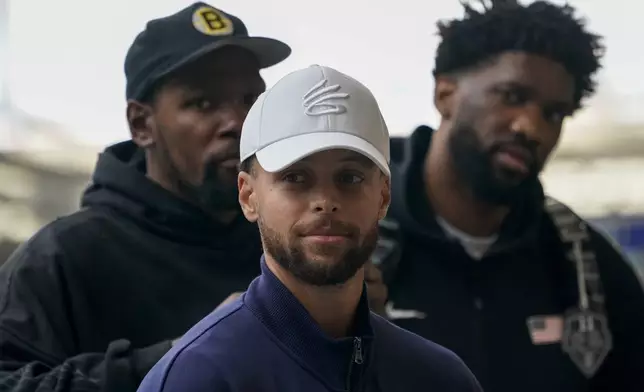 United States' Steph Curry, centre, Kevin Durant, background left, and Joel Embiid arrive at St Pancras Station with teammates, to take the Eurostar train as they make their way to the Olympic Games in Paris, in London, Wednesday, July 24, 2024.(AP Photo/Alberto Pezzali)