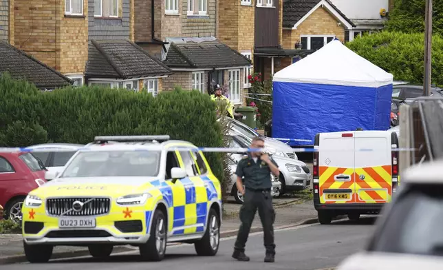 Police and emergency services at the scene in Ashlyn Close, after an incident on Tuesday evening, in Bushey, Hertfordshire, England, Wednesday, July 10, 2024. British police were hunting for a man believed to be armed with a crossbow on Wednesday after three women were killed in a house near London. The BBC said the women killed were the family of its main radio racing commentator John Hunt. (James Manning/PA via AP)