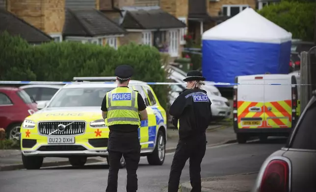 Police and emergency services at the scene in Ashlyn Close, after an incident on Tuesday evening, in Bushey, Hertfordshire, England, Wednesday, July 10, 2024. British police were hunting for a man believed to be armed with a crossbow on Wednesday after three women were killed in a house near London. The BBC said the women killed were the family of its main radio racing commentator John Hunt. (James Manning/PA via AP)