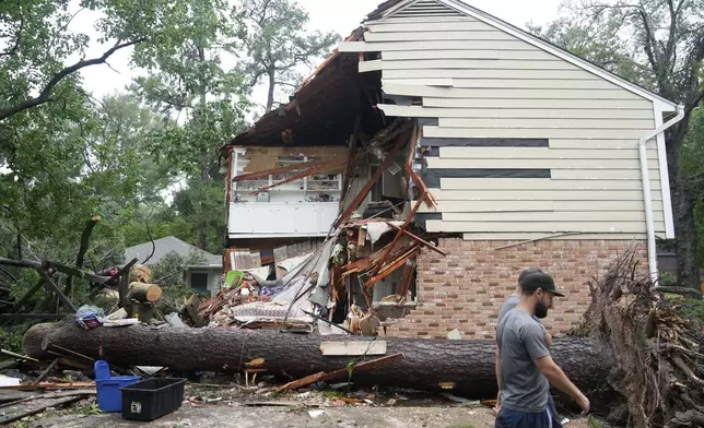 CORRECTION CORRECTS NAME People gather outside a home in the 17400 block of Rustic Canyon Trail where Maria Loredo, 74, died after a tree fell on her second story bedroom during Hurricane Beryl Monday, July 8, 2024, in Houston. (Melissa Phillip/Houston Chronicle via AP)