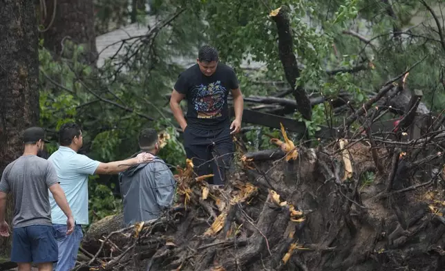 CORRECTION CORRECTS NAME People gather outside a home in the 17400 block of Rustic Canyon Trail where Maria Loredo, 74, died after a tree fell on her second story bedroom during Hurricane Beryl Monday, July 8, 2024, in Houston (Melissa Phillip/Houston Chronicle via AP)