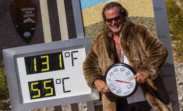 Thor Teigen poses in a fur jacket next to a thermometer displaying a temperature of 131 degrees Fahrenheit / 55 degrees Celsius at the Furnace Creek Visitors Center, in Death Valley National Park, Calif., Sunday, July 7, 2024. Forecasters said a heat wave could break previous records across the U.S., including at Death Valley. (AP Photo/Ty ONeil)