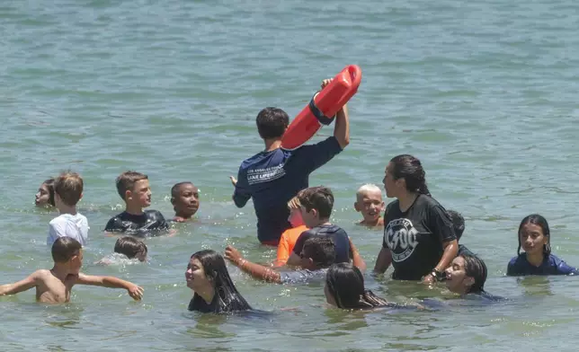 A Los Angeles County Lifeguard keeps children safe as they cool off at Castaic Lake as temperatures rise, Monday, July 8, 2024, in Castaic, Calif. (AP Photo/Damian Dovarganes)