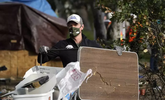 FILE - California Gov. Gavin Newsom helps clean a homeless encampment alongside a freeway, Wednesday, Jan. 12, 2022, in San Diego. Newsom issued an executive order Thursday, July 25, 2024, for the removal of homeless encampments in the state. (AP Photo/Gregory Bull, File)