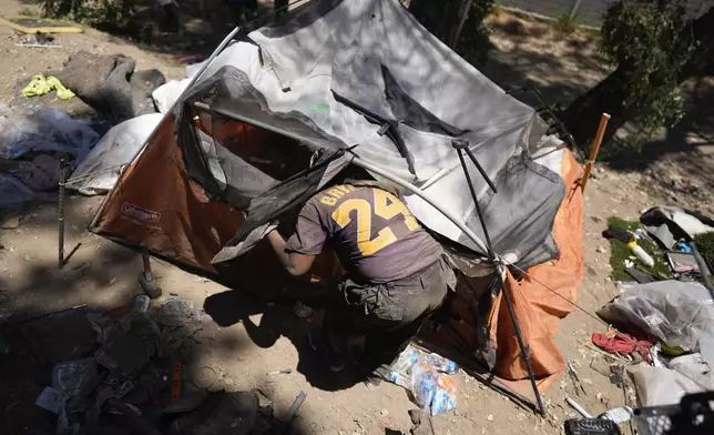 Esca Guernon enters her tent at a homeless encampment next to the 405 Freeway in the Van Nuys section of Los Angeles on Friday, July 26, 2024, in Los Angeles. California Gov. Gavin Newsom has issued an executive order directing state agencies "to move urgently to address dangerous" homeless encampments and clear them from state land while giving city and local leaders a push to do the same. (AP Photo/Jae C. Hong)