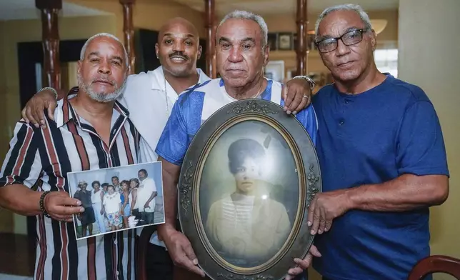 Descendants of Nelson Bell, relatives from left, William Woolery, Trent Mure, and brothers, Milford Fonza and Elmer Fonza, far right, gather around a picture of their ancestor Ethel Bell while showing family pictures in Glendora, Calif., on Friday, Sept. 8, 2023. (AP Photo/Damian Dovarganes)