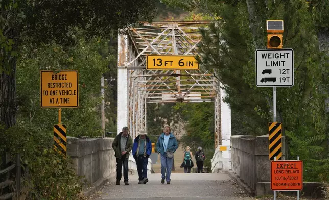 People cross Mt. Murphy Road Bridge into the Marshall Gold Discovery State Historic Park, Tuesday, Oct. 10, 2023, in Coloma, Calif. (AP Photo/Godofredo A. Vásquez)