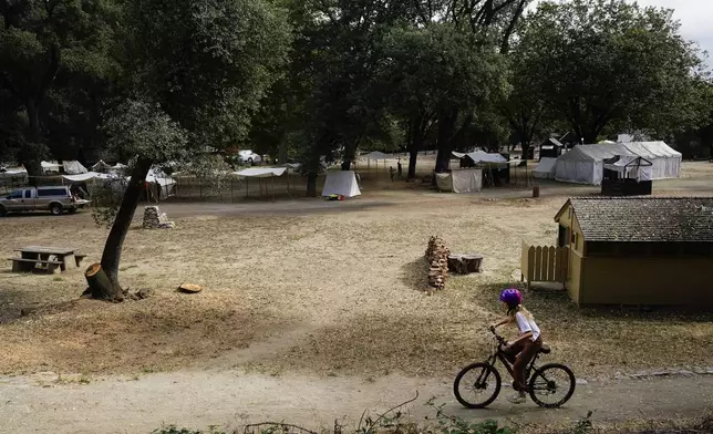 A girl rides a bicycle on a trail at the Marshall Gold Discovery State Historic Park, Tuesday, Oct. 10, 2023, in Coloma, Calif. (AP Photo/Godofredo A. Vásquez)