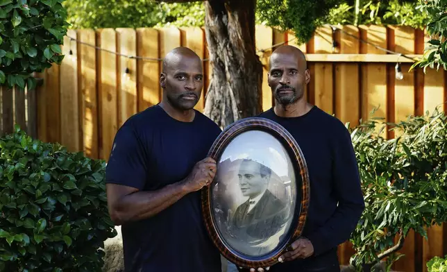 Matthew, left, and his twin brother Jonathan Burgess are photographed with a portrait of their great-great-grandfather Nelson Bell, who the family say also went by the name Rufus Burgess, Monday, Oct. 9, 2023, in Sacramento, Calif. The portrait has been passed down for generations in the Burgess family. (AP Photo/Godofredo A. Vásquez)