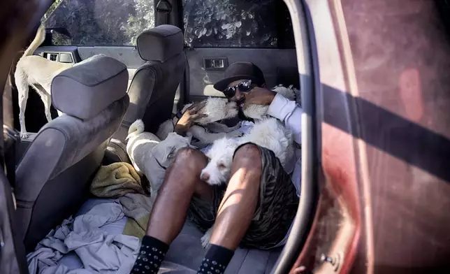 David Clarke who is suffering homelessness and living in his car with his 6 dogs, takes to the shade at the Sepulveda Basin dog park in Los Angeles on Tuesday, July 9, 2024. Dozens of locations in the West and Pacific Northwest tied or broke previous heat records over the weekend and are expected to keep doing so into the week. (AP Photo/Richard Vogel)