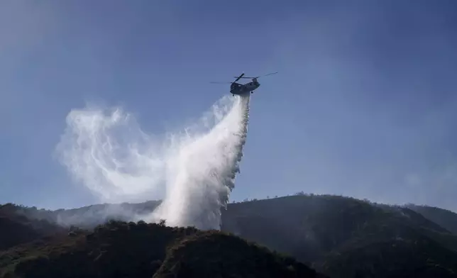 A helicopter drops water on a hillside during the Sharp Fire in Simi Valley, Calif., Wednesday, July 3, 2024. (AP Photo/Eric Thayer)