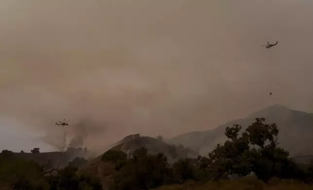 Helicopters drop water on flames from the advancing Lake Fire in Los Olivos, Calif., Saturday, July 6, 2024. (AP Photo/Eric Thayer)