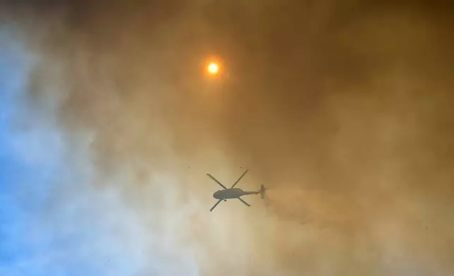 A helicopter drops water on the Park Fire burning near Forest Ranch, Calif., Saturday, July 27, 2024. (AP Photo/Nic Coury)