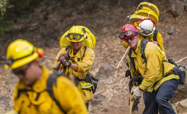 Firefighters carry hose near a home to fight the Park Fire near Forest Ranch, Calif., Saturday, July 27, 2024. (AP Photo/Nic Coury)