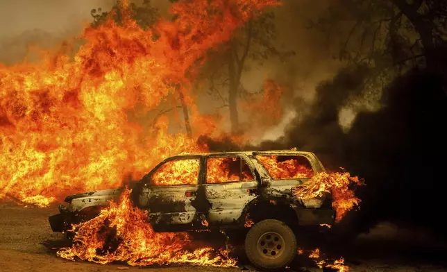 Flames consume a car and building as the Park Fire tears though the Cohasset community in Butte County, Calif., on Thursday, July 25, 2024. (AP Photo/Noah Berger)