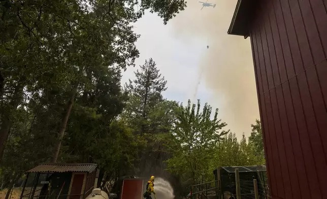 Volunteer firefighter Craig Klieb sprays water around his house as the Park Fire burns nearby in Forest Ranch, Calif., Saturday, July 27, 2024. Until a few years ago, (AP Photo/Nic Coury)