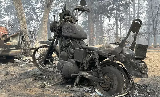 A charred motorcycle is seen in aftermath of the Park Fire, Sunday, July 28, 2024, in the Cohasset community of Butte County, Calif. (AP Photo/Eugene Garcia)