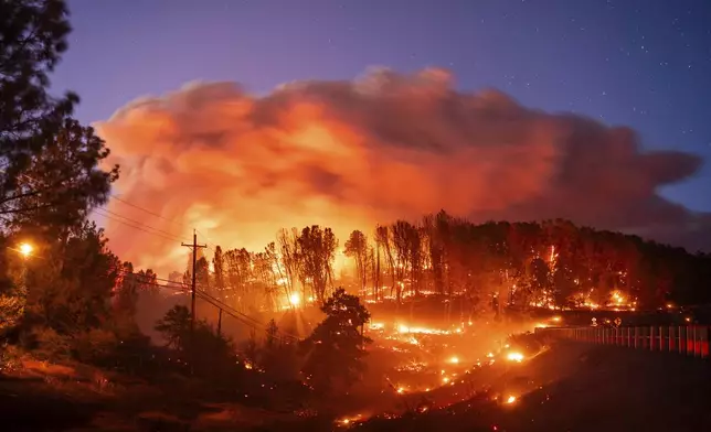 Seen in a long exposure photograph, the Park Fire burns along Highway 32 in the Forest Ranch community of Butte County, Calif., on Thursday, July 25, 2024. (AP Photo/Noah Berger)