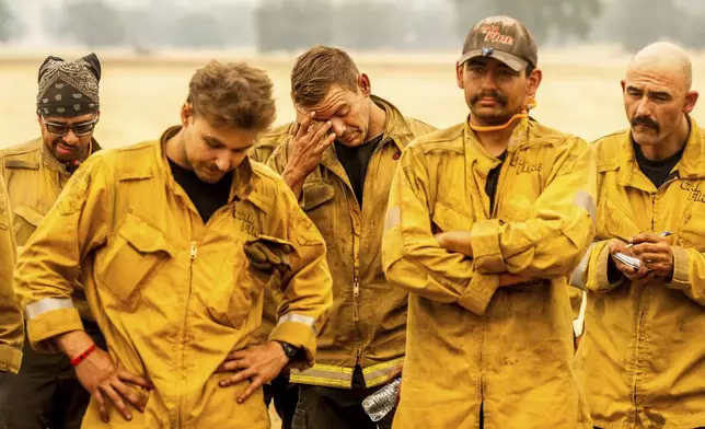 Firefighter Michael Benson, center, rubs his face during a briefing while battling the Park Fire in Tehama County, Calif., on Saturday, July 27, 2024. (AP Photo/Noah Berger)