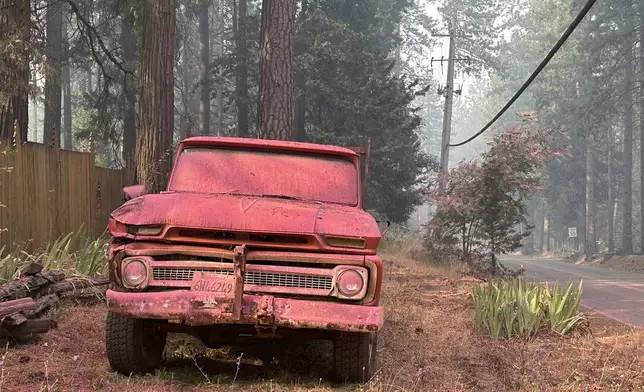 A vehicle is doused with retardant in the aftermath of the Park Fire, Sunday, July 28, 2024, in the Cohasset community of Butte County, Calif. (AP Photo/Eugene Garcia)