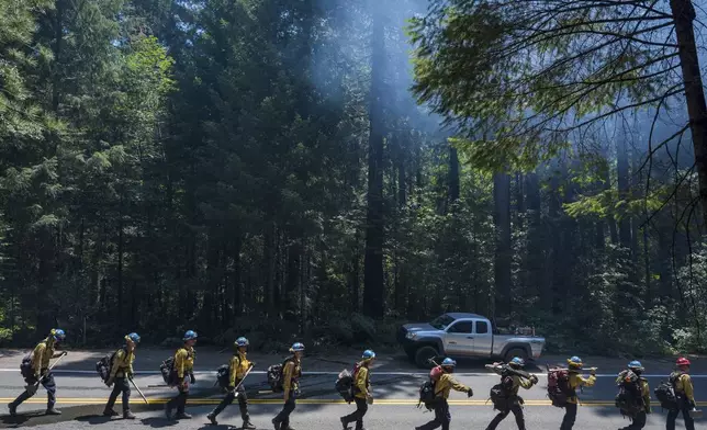 A fire crew walks along Highway 32 near Butte Meadows, Calif., Tuesday, July 30, 2024. (AP Photo/Nic Coury)