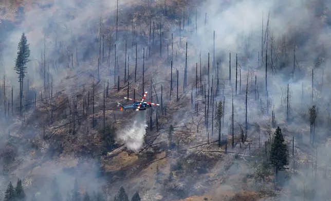 A helicopter drops water on the Park Fire near Butte Meadows, Calif., Tuesday, July 30, 2024. (AP Photo/Nic Coury)