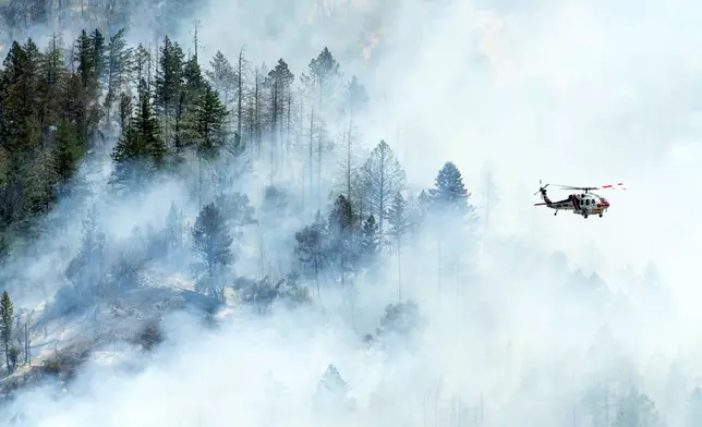 A helicopter flies above smoke as the Toll Fire burns near Calistoga, Calif., on Tuesday, July 2, 2024. An extended heatwave blanketing Northern California has resulted in red flag fire warnings and power shutoffs. (AP Photo/Noah Berger)