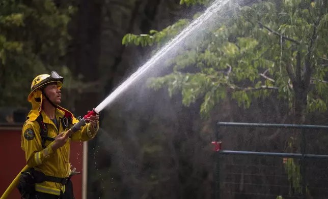 Volunteer firefighter Craig Klieb sprays water around his house as the Park Fire burns nearby in Forest Ranch, Calif., Saturday, July 27, 2024. (AP Photo/Nic Coury)