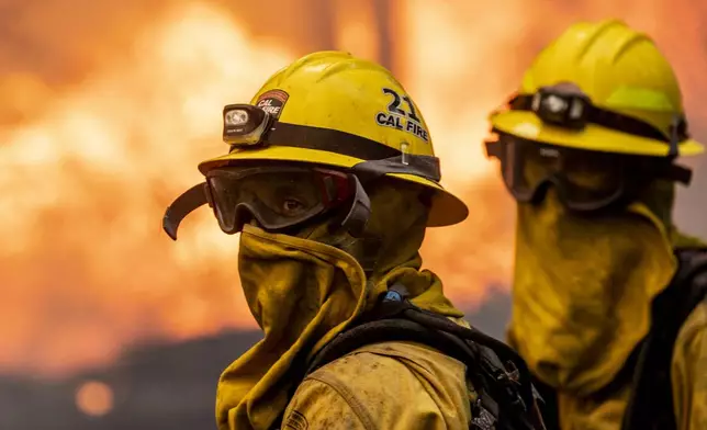 Cal Fire firefighter Christian Moorhouse, center, monitors the flames while defends a mobile home during the Park Fire in the community of Cohasset near Chico, Calif., Thursday, July 25, 2024. (Stephen Lam/San Francisco Chronicle via AP)