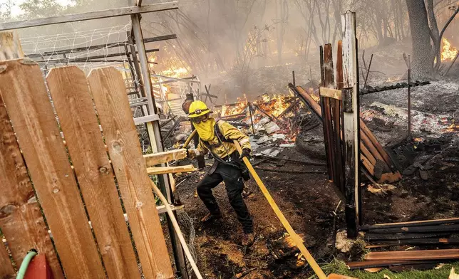 Firefighter Christian Moorhouse battles the Park Fire tears through the Cohasset community in Butte County, Calif., on Thursday, July 25, 2024. His crew was able to keep flames from reaching the mobile home they were protecting. (AP Photo/Noah Berger)