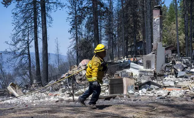 A firefighter walks by the remains of a home that was destroyed in the Park Fire near Forest Ranch, Calif., Tuesday, July 30, 2024. (AP Photo/Nic Coury)