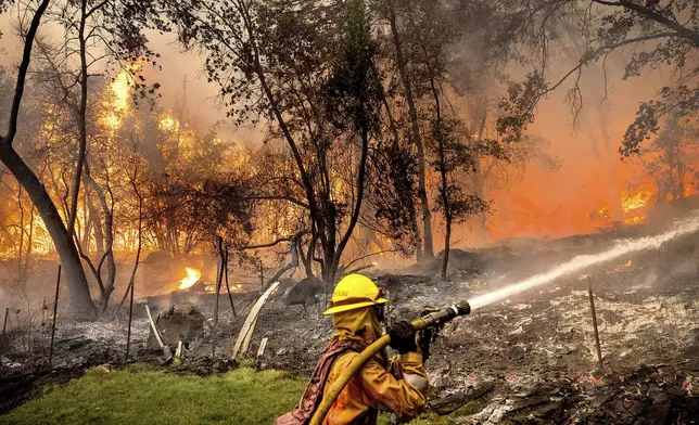 Firefighter Christian Moorhouse battles the Park Fire tears through the Cohasset community in Butte County, Calif., on Thursday, July 25, 2024. His crew was able to keep flames from reaching the mobile home they were protecting. (AP Photo/Noah Berger)