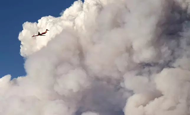 Seen from Chico, Calif., an air tanker passes a plume from the Park Fire burning in Butte County on Thursday, July 25, 2024. (AP Photo/Noah Berger)